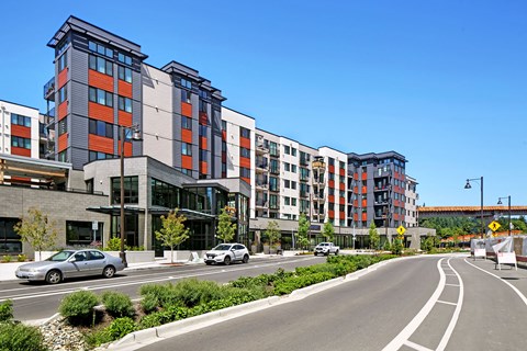a street view of an apartment building with cars on the road