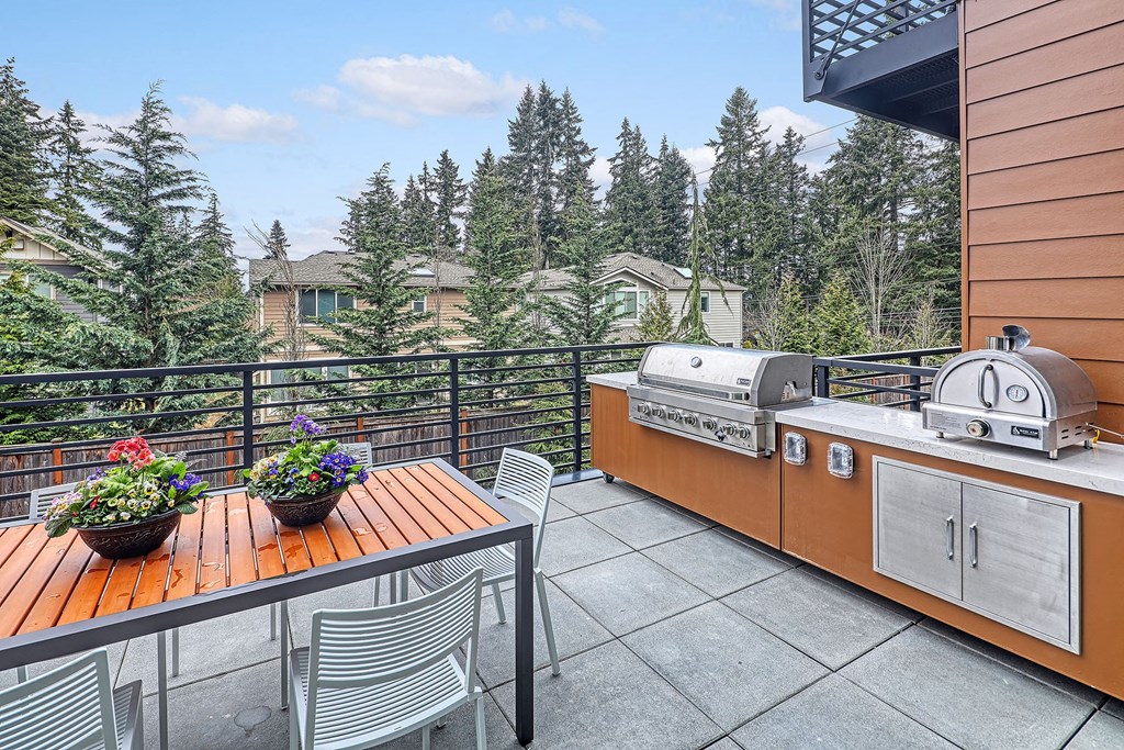 the deck has a gas grill and a dining table with four chairs