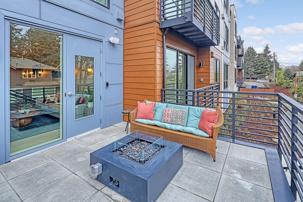 a patio with a firepit and a couch on a balcony