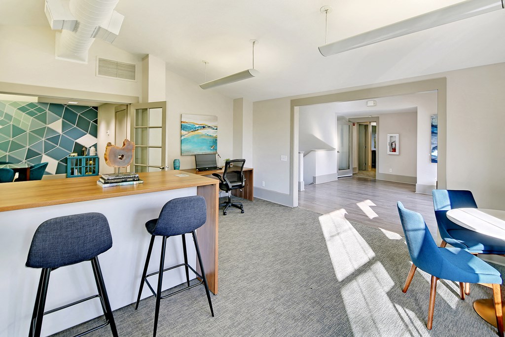 a living room with a bar and chairs and a dining room