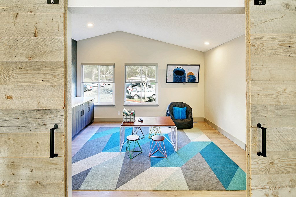 a living room with a blue rug and a table and chairs