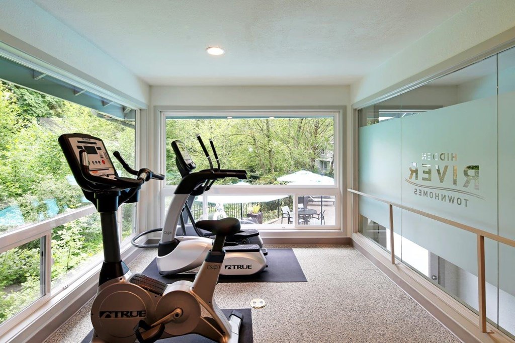 a gym with a view of a pool and trees