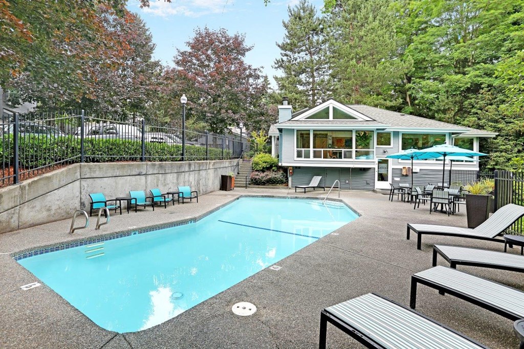 a pool with chairs and a house in the background