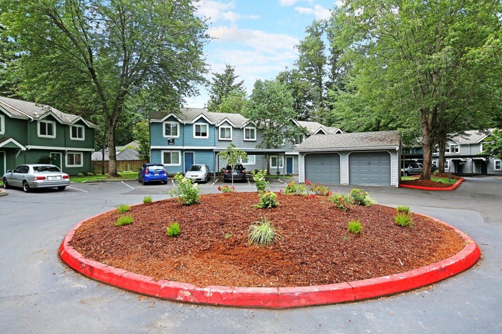 a circle of landscaping in a parking lot in front of houses