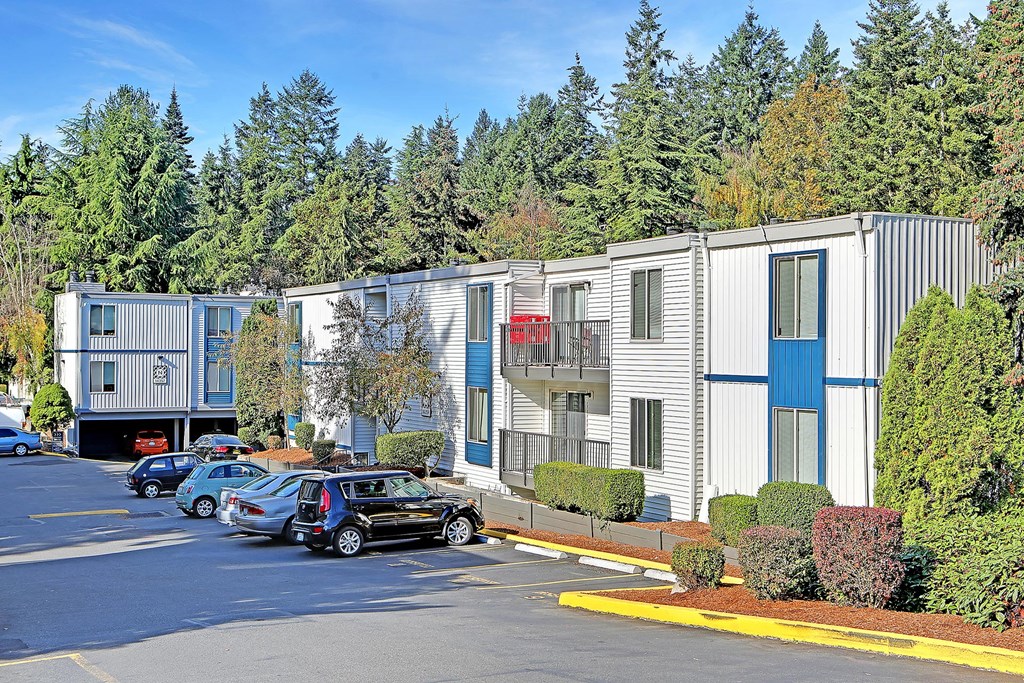 A parking lot with cars and apartment buildings.