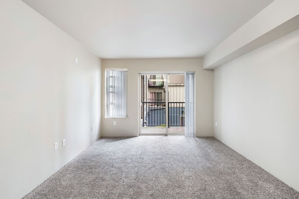 an empty living room with a door to a balcony