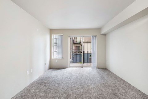 an empty living room with a door to a balcony