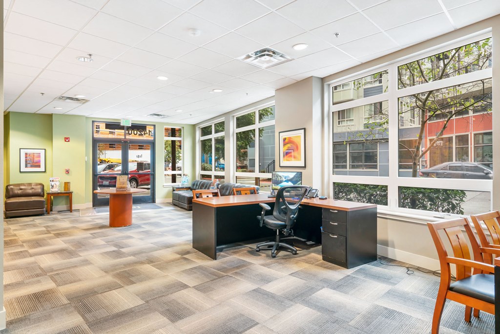 a conference room with a desk and chairs and large windows