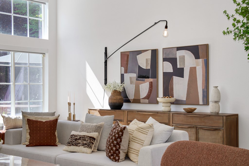 A living room with a couch, pillows, and a large abstract painting on the wall.