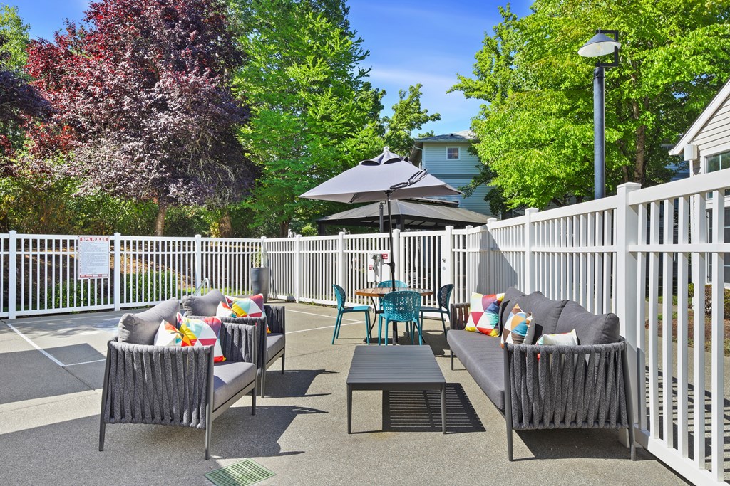 A patio with a white fence and a black umbrella.