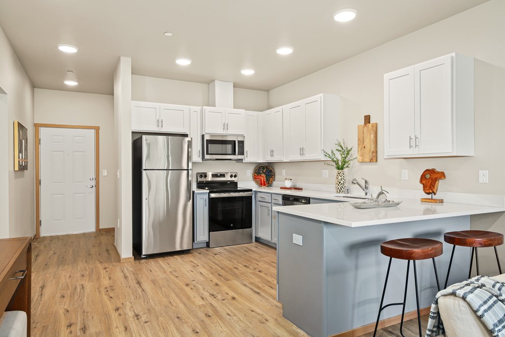 A kitchen with white cabinets and a wooden floor.