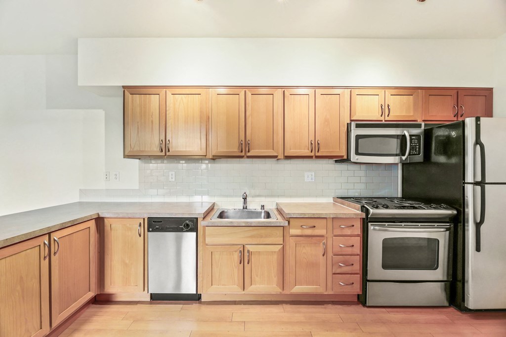 an empty kitchen with wooden cabinets and stainless steel appliances
