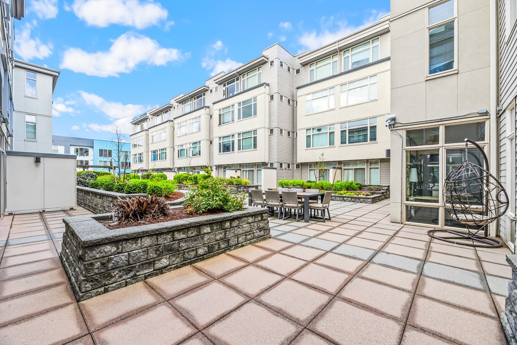 a patio with a stone wall and a table and chairs in front of a building