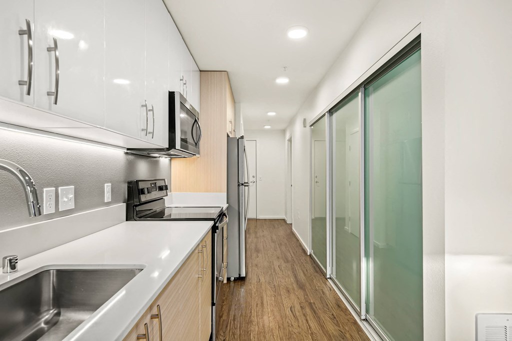 A modern kitchen with stainless steel appliances and wooden floors.