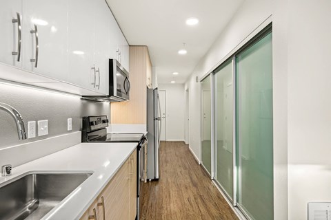 A modern kitchen with stainless steel appliances and wooden floors.