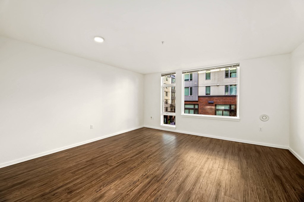A room with wooden flooring and a window showing a building outside.