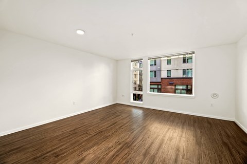 A room with wooden flooring and a window showing a building outside.
