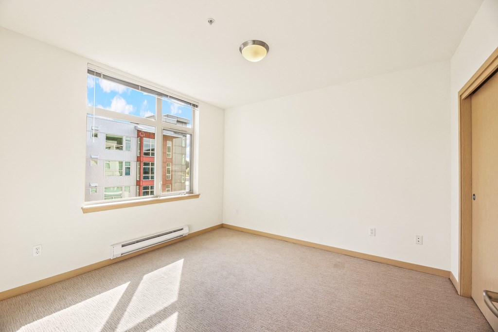 an empty living room with a large window and white walls