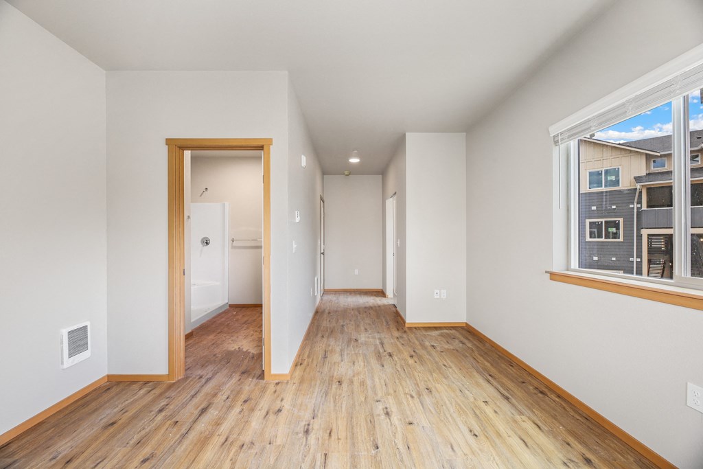 a living room with a wooden floor and a door to a hallway