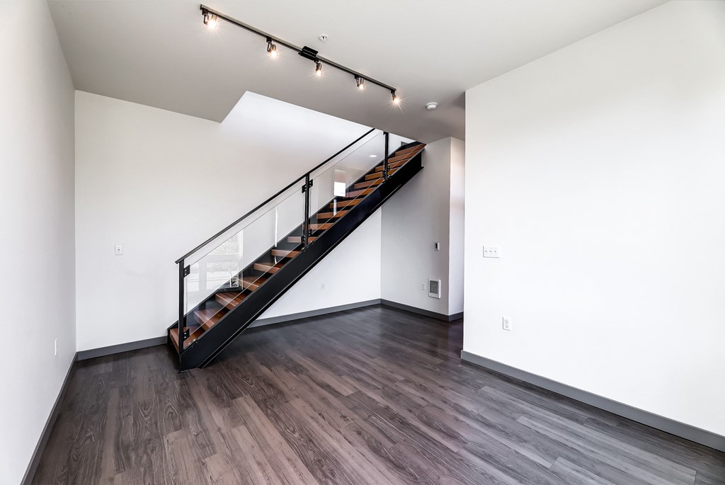 a living room with wood floors and a staircase with a glass railing