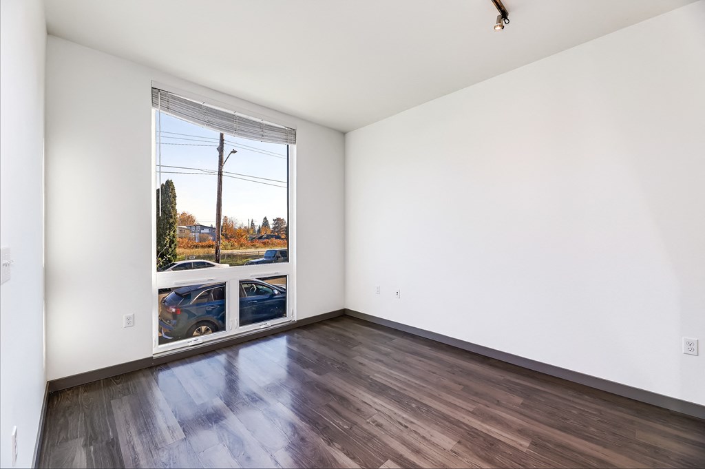 an empty living room with a large window and wooden floors