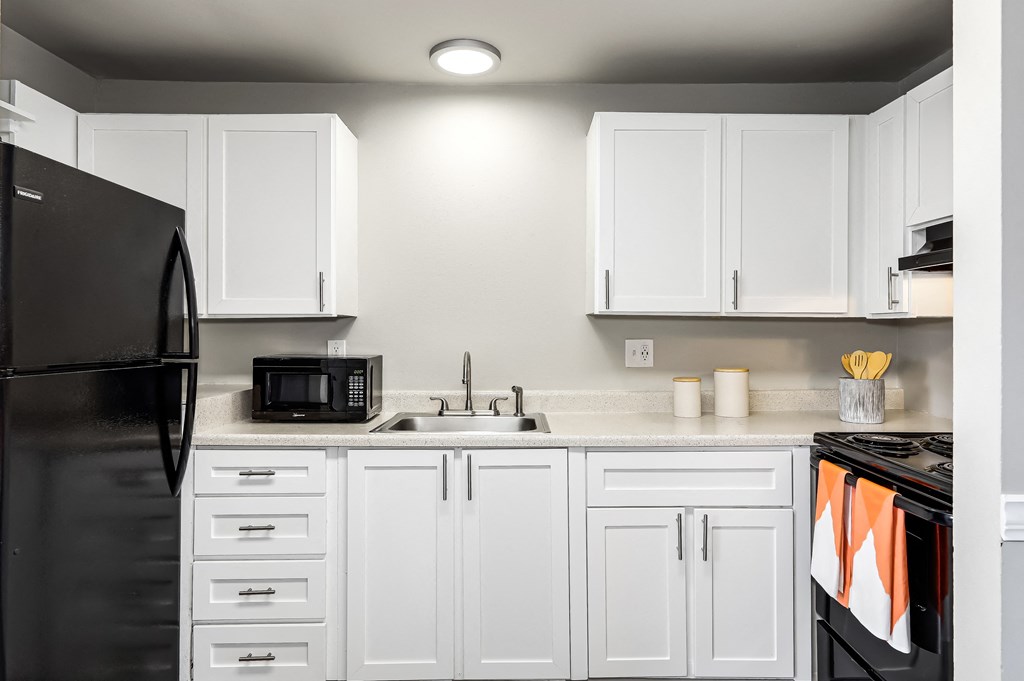 a kitchen with white cabinets and black appliances