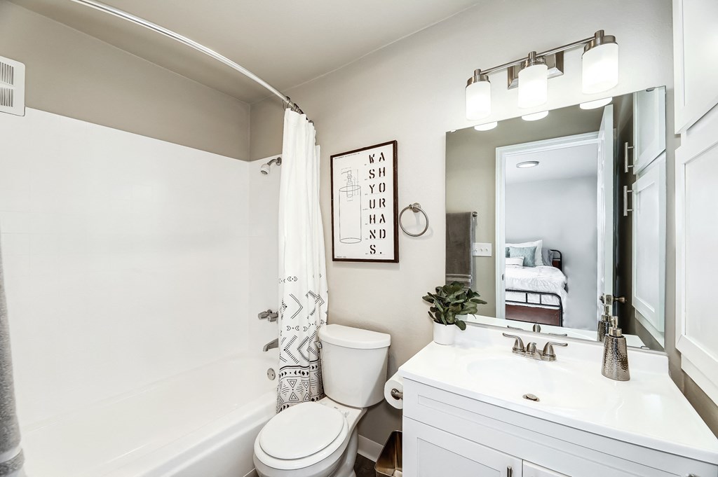 a bathroom with a white sink and toilet next to a bathtub with a shower curtain and