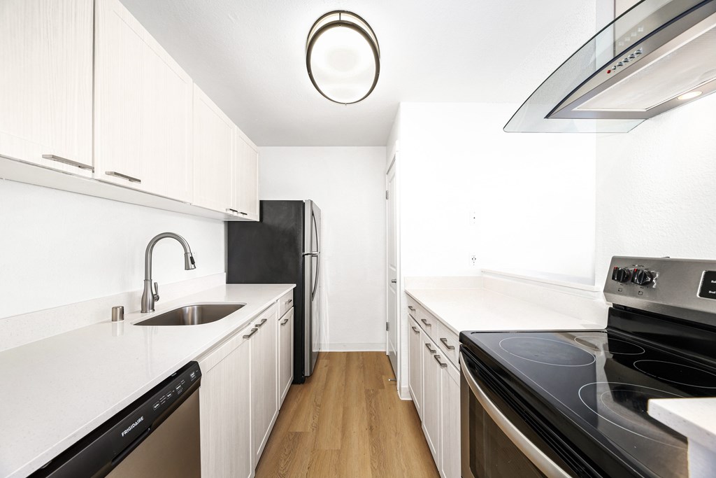 A modern kitchen with white cabinets and black appliances.