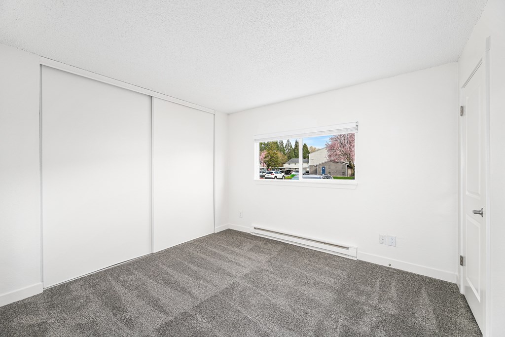 A room with a grey carpet and a white wall with a picture of a house on it.