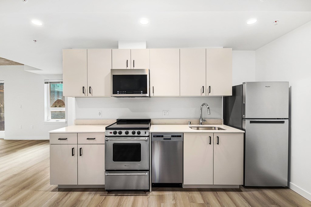 A modern kitchen with stainless steel appliances and wooden floors.