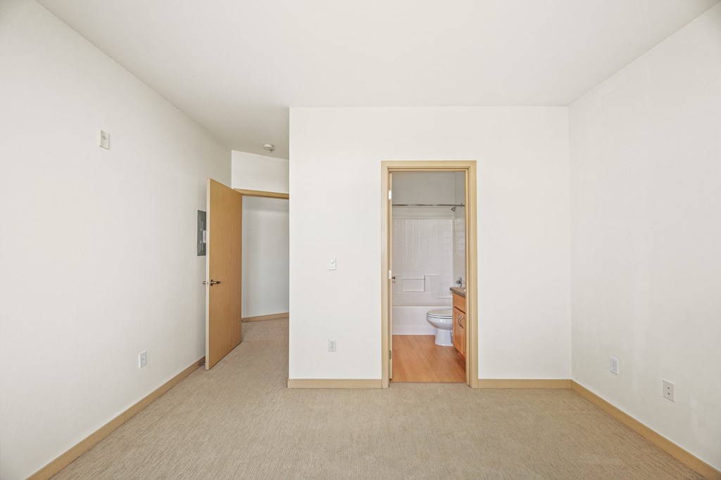 a living room with white walls and a door to a bathroom