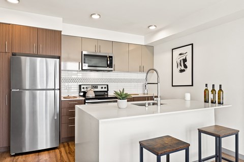 a kitchen with a large island and stainless steel refrigerator