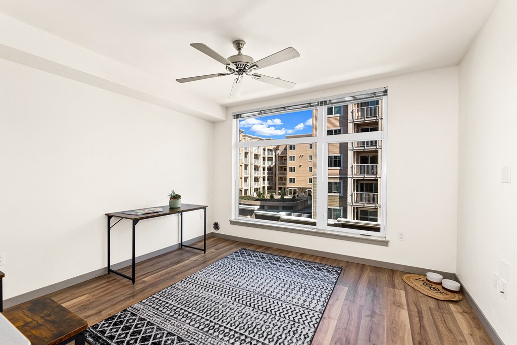 a bedroom with a large window and hardwood floors.