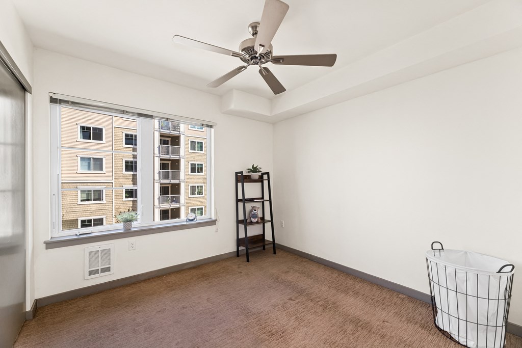 a bedroom with a large window and a ceiling fan