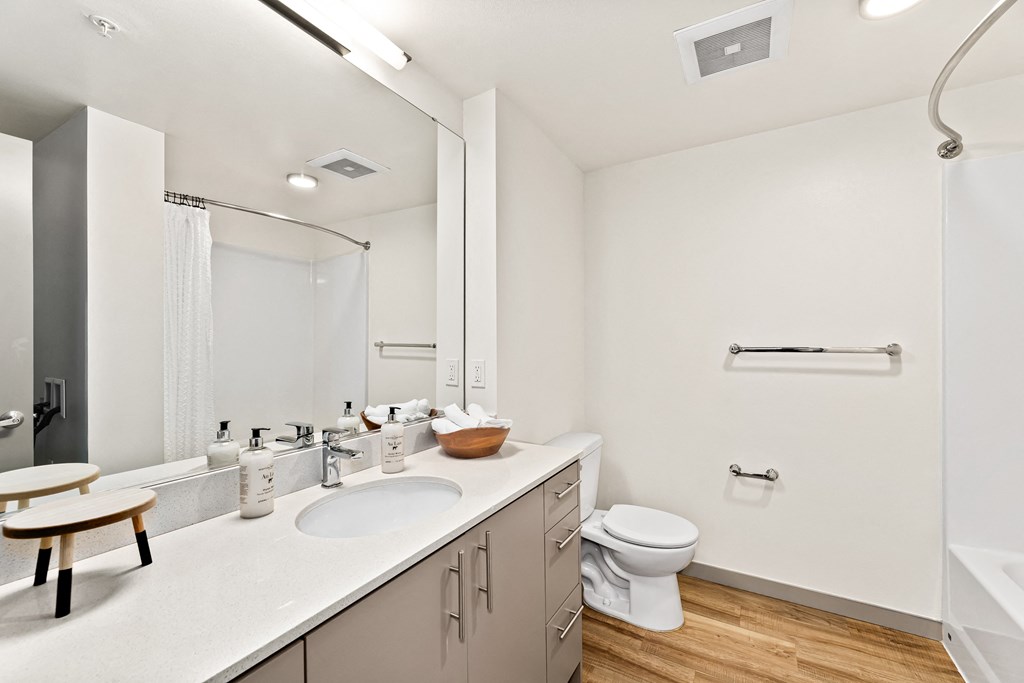 a bathroom with white walls and wood flooring