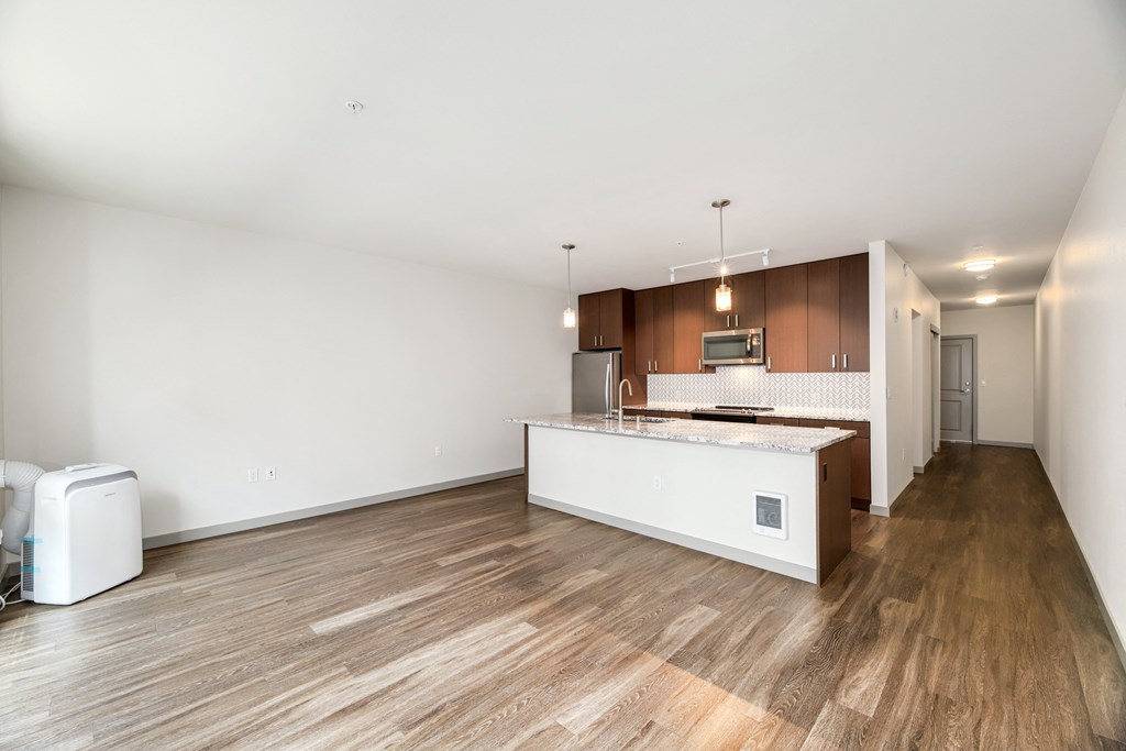 an empty living room and kitchen with a large island and wood floors