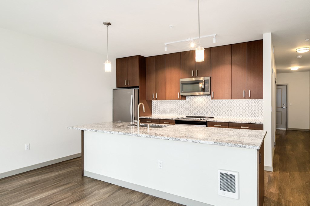 a kitchen with a large island with granite counter tops and wooden cabinets