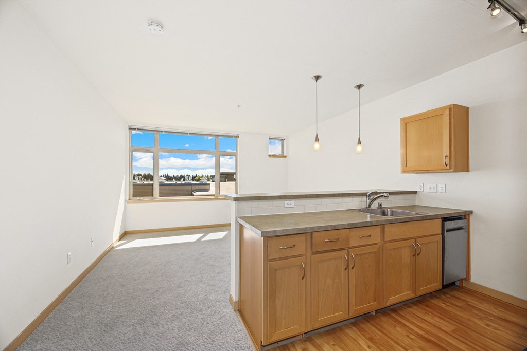 an empty kitchen with wooden cabinets and a sink and a window