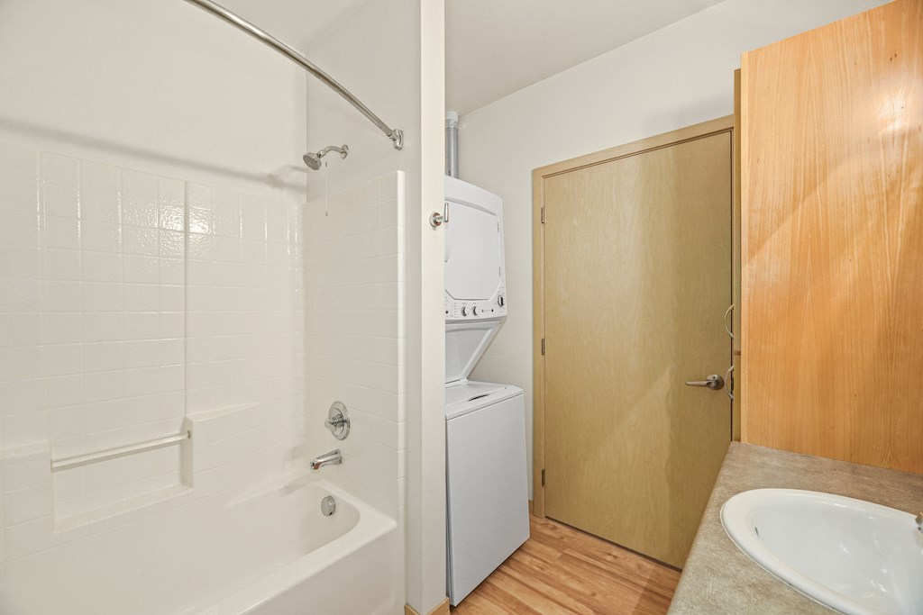 a bathroom with a sink and a shower and a washer and dryer