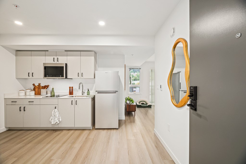 A modern kitchen with white cabinets and a wooden floor.