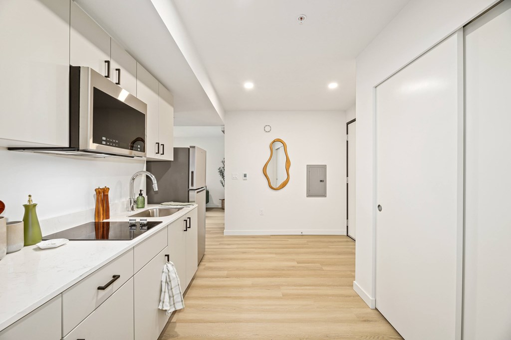 A modern kitchen with white cabinets and a wooden floor.