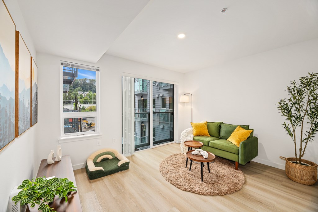 A living room with a green couch and a wooden floor.