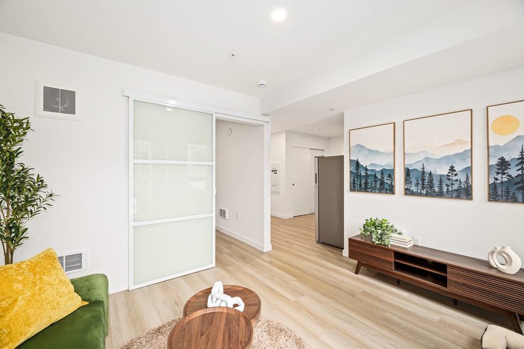 A living room with a green couch, a coffee table, and a painting on the wall.