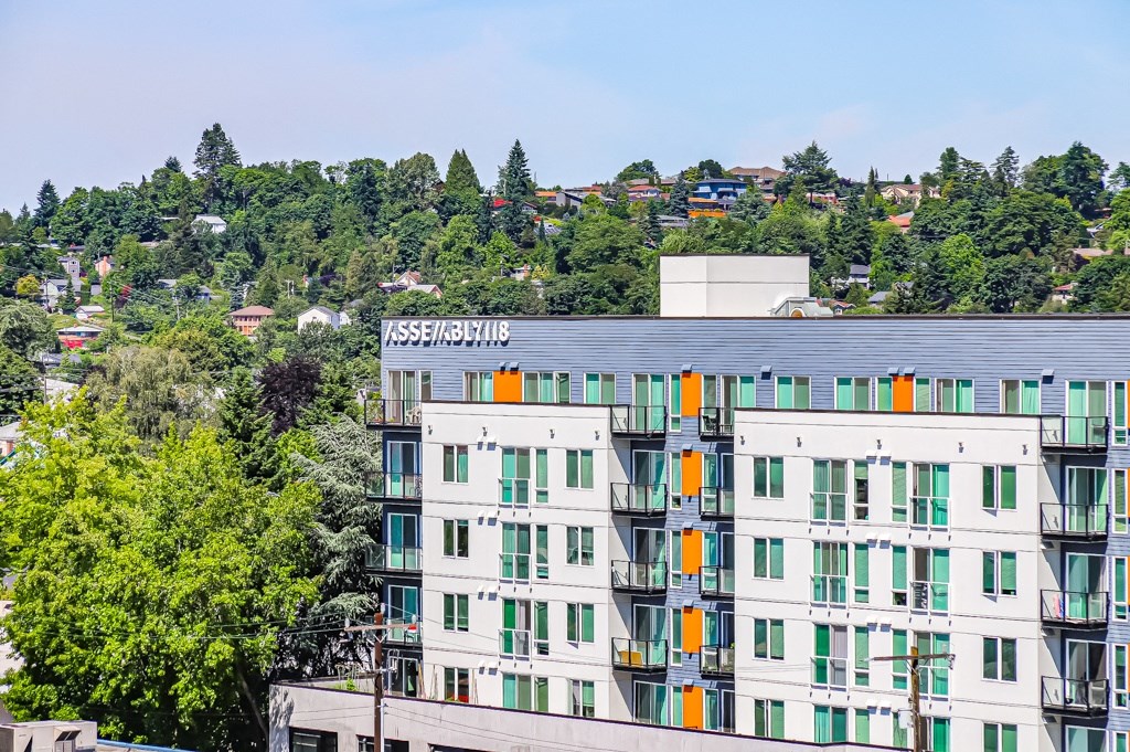 a white apartment building with green windows and a hill in the background