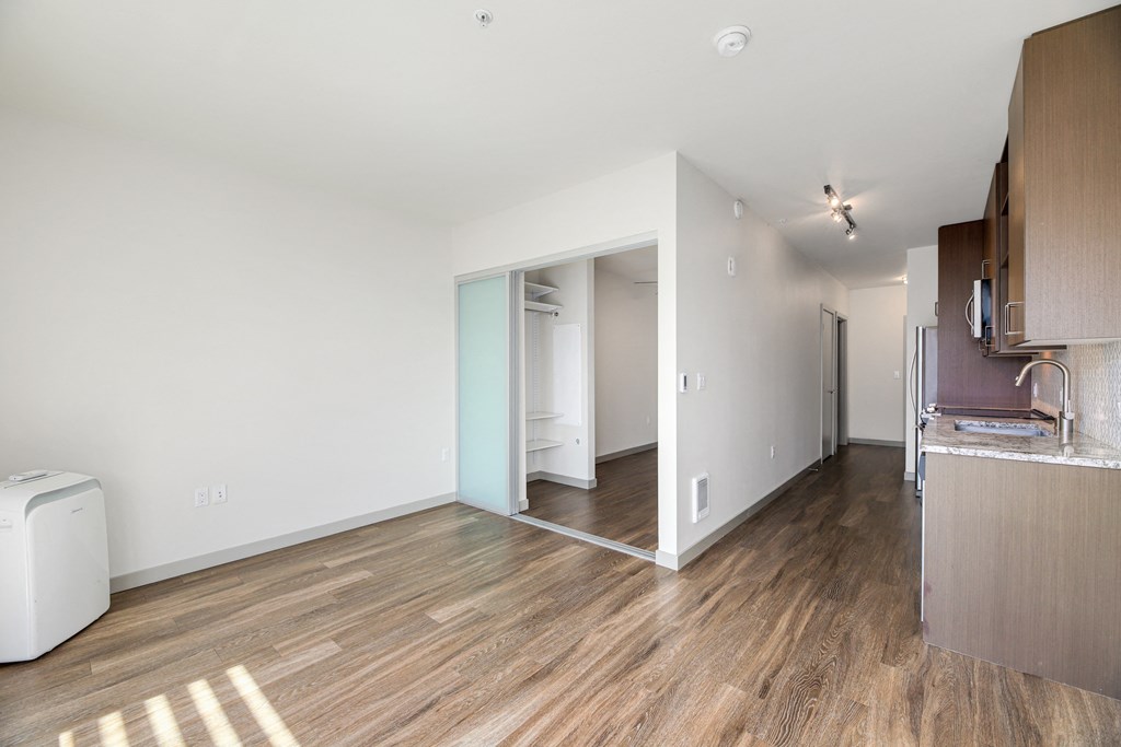 a living room and kitchen with wood flooring and white walls