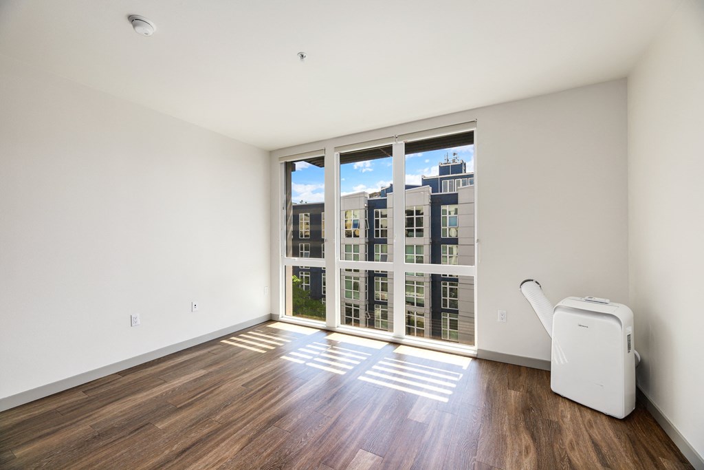an empty living room with a large window and hardwood floors