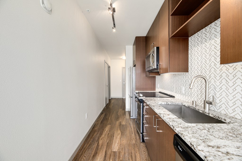 a kitchen with marble counter tops and wooden cabinets and a sink