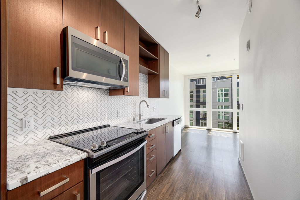 a kitchen with marble counter tops and wooden cabinets and a microwave over the stove
