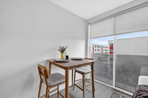 A dining table with two chairs and a vase of flowers on it.
