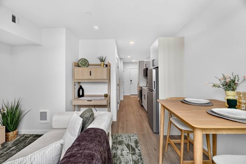 A modern living room with a white sofa and a wooden dining table.
